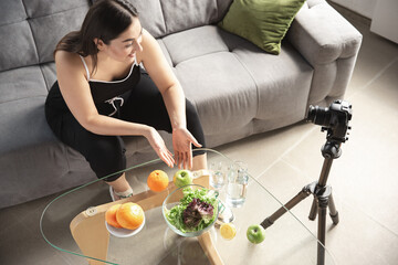 Organic. Caucasian blogger, woman make vlog how to diet and lost weight, be body positive, healthy eating. Using camera recording her fruits salad preparing. Lifestyle influencer, wellness concept.
