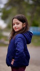 Fototapeta premium Portrait of a pretty little girl with long loose hair in a park