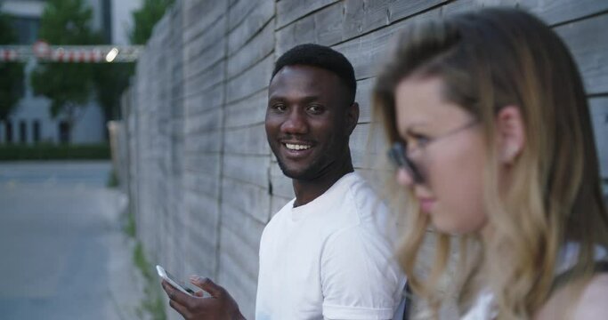 Young Black Man Smiling at Camera Woman in Foreground