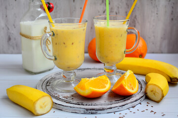 Banana-citrus milkshake in tall glasses on a light background. Healthy lifestyle