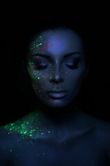 Fashion model woman in neon light bright fluorescent makeup, drop on face. Beautiful model brunette girl colorful make-up, painted skin, body art design ultraviolet