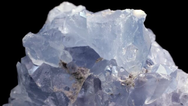 Blue celestine mineral crystals macro video with slow rotation over a black background