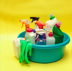 Set of cleaning products and detergents in a blue basin, on a yellow background. Cleaning, disinfection. Sanitation.cleaning. Space for text.