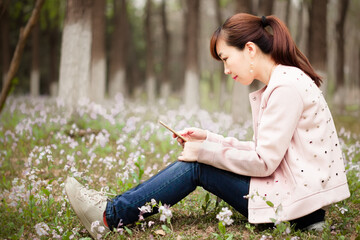 Sitting leisurely on the lawn of a park and browsing the phone on a spring afternoon.