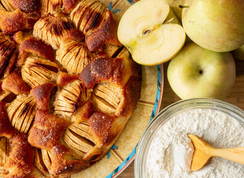overhead view of an apple pie along with some apples and a jar of arina