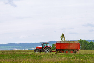 The harvester collects freshly cut grass into a tractor trailer.