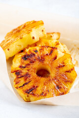 Heap of grilled pineapple slices on white background.