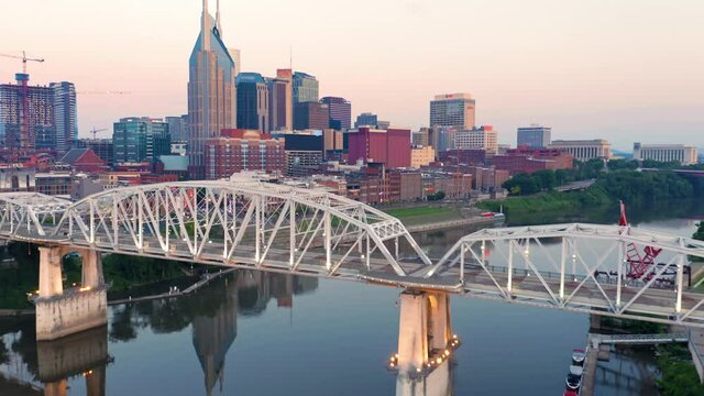 Aerial: Downtown Nashville, Cumberland River & pedestrian bridge at sunrise. Tennessee, USA