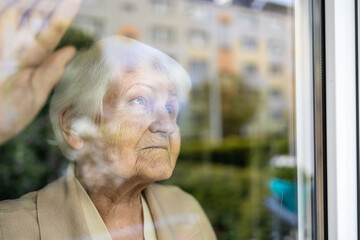 Senior woman looking out of window at home
