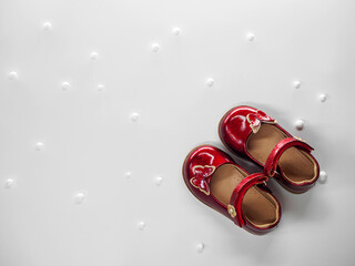Flat lay with red patent leather childrens shoes with red butterfly and clasps fasteners and with white balls at white background