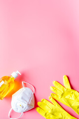 Gloves, sanitizer, mask - viruses prevention - on pink desk flat lay copy space