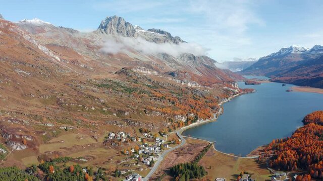 4k drone flight moving to the side and down footage (Ultra High Definition). Sunny autumn view of Sils lake, Swiss Alps. Aerial outdoor scene of Maloya village, Switzerland, Europe. 