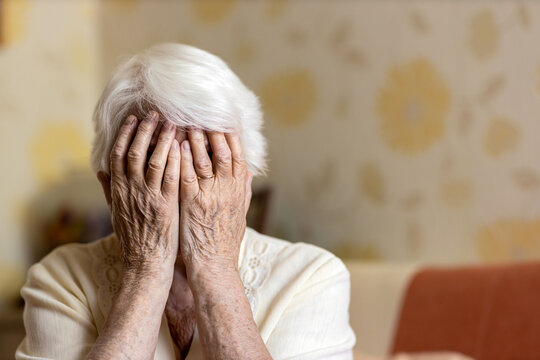 Senior Woman Holding Head In Hands In Despair 
