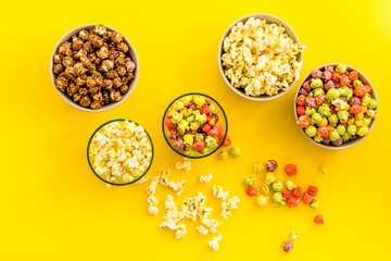 Flavored popcorn on yellow background top view