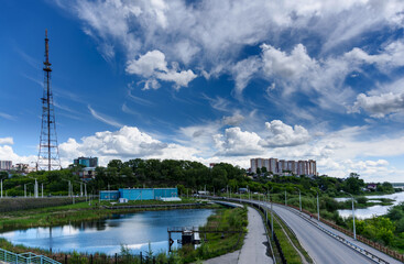 Obraz premium Panoramic view to Irkutsk city, small pond with reflection, TV tower and road from the academic bridge in sunny summer day with beautiful clouds