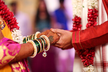 Indian bride and groom holding each others hand during wedding
