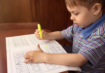 little boy is learning to write with a yellow felt tip pen