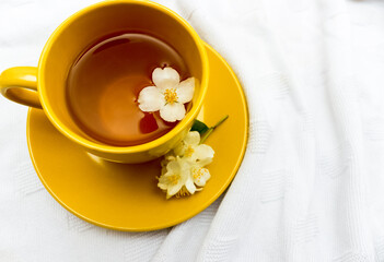 yellow cup of tea with jasmine flowers on a wooden background. Chinese jasmine tea, healthy life