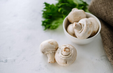 Champignon mushrooms in a white bowl with herbs on the table close-up.