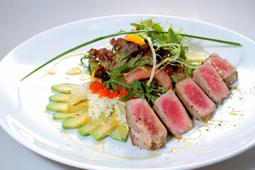 Salad with tuna, avocado, arugula and caviar on a white plate