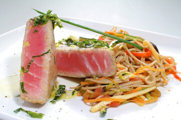 Soy noodles with tuna and vegetables on a white plate