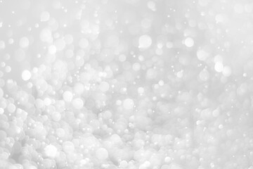 White glitter vintage lights background. White bokeh on black background.