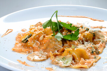 Ravioli with sauce, parmesan and parsley on a white plate