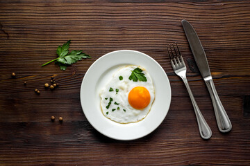 Fried eggs on plate - dark wooden table top view