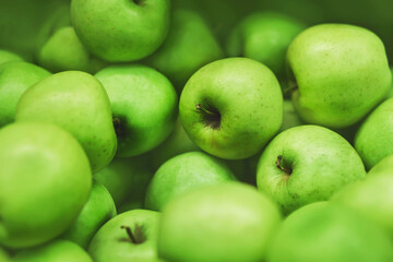 Green ripe sweet delicious apples are lying in a pile in the grocery store. Vegetarianism. Fruit.