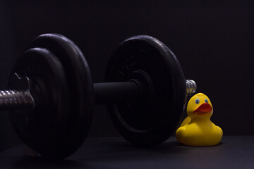 Black metal dumbbell for fitness with a duck, on a black background.