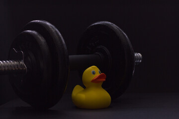 Fototapeta na wymiar Black metal dumbbell for fitness with a duck, on a black background.