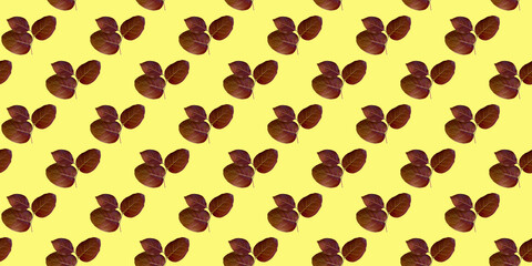 Seamless pattern of maroon leaves on a yellow background. Seasonal natural background. Autumn texture