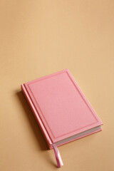 Fototapeta premium Cover of pink notebook, diary or book on brown paper background