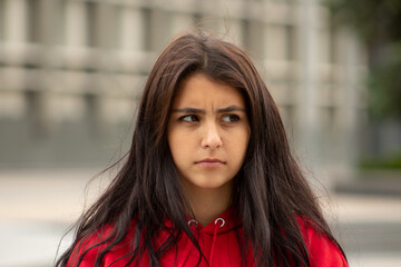 Portrait of offended girl with dark hair on the street