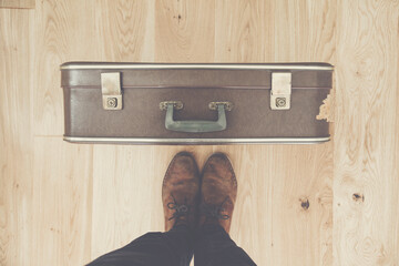 Looking down towards a persons feet and old vintage travel suitcase