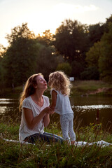 Fototapeta premium Mom and daughter on the street are looking at each other. Laughter and joy of a woman and a child. High quality photo