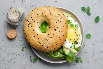 Bagel with avocado, egg and salad on plate. Healthy morning breakfast