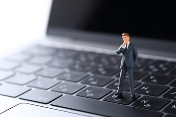 ノーパソコンに置いたビジネスマンの人形