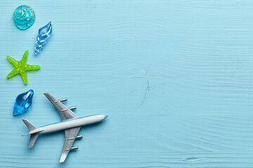 Vacation and sea flight concept with airplane and glass shells on wooden blue background with copy space.