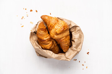 Croissants in paper bag on white background. Minimalism concept, close-up view, top view