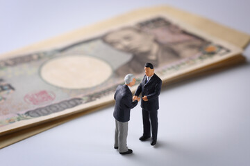 一万円札とビジネスマンの人形