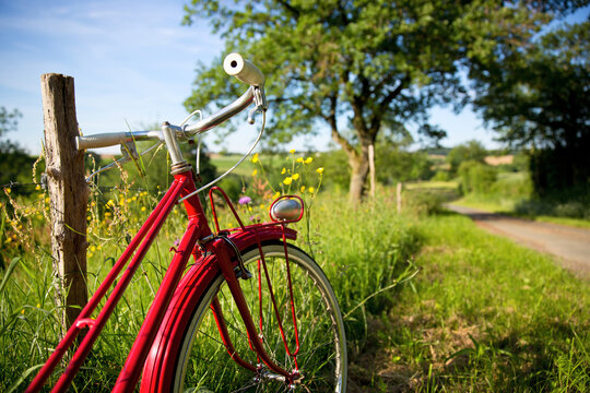 Vieux vélo rouge sur un chemin de campagne en France.