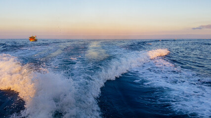 Passing by a boat with a yacht in Malta at sunset