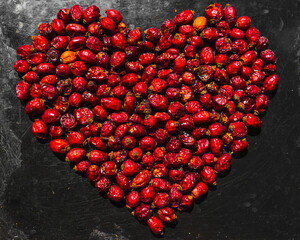 heart made of rose hips on a baking sheet metal background. heart of red rosehip berries.