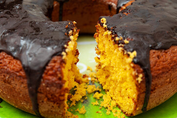 Close-up of delicious and healthy traditional Brazilian homemade carrot cake with chocolate sauce. Background with crochet towel. Horizontal shot.