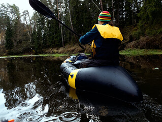 River rafting in the fall. A young man rafts in a boat on a river in the wild. Packrafting in...