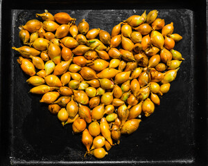 heart made of bulb onions on a background of baking sheet metal. heart formed from bulb onions.