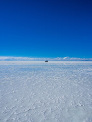 Fototapeta na wymiar Car crossing the salt flat Salar de Uyuni in Bolivia