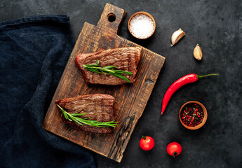 Fototapeta na wymiar Two grilled beef steaks with spices on a stone background