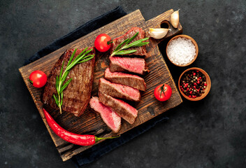 
Two grilled beef steaks with spices on a stone background